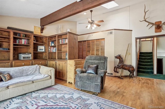 living area with light wood-type flooring, lofted ceiling with skylight, and ceiling fan