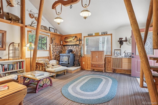 living area featuring wood walls, high vaulted ceiling, and a wood stove