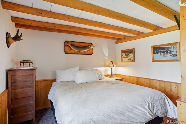 bedroom with wood walls and beam ceiling