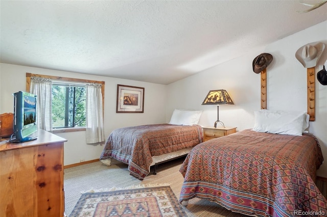 bedroom featuring a textured ceiling, light colored carpet, and vaulted ceiling