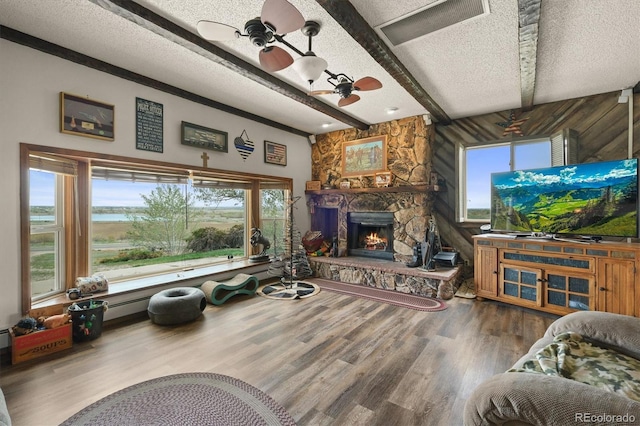 12101 Riverdale Rd, Brighton, CO 80602 - living room featuring ceiling fan, a stone fireplace, a textured ceiling, wood finished floors, and beam ceiling