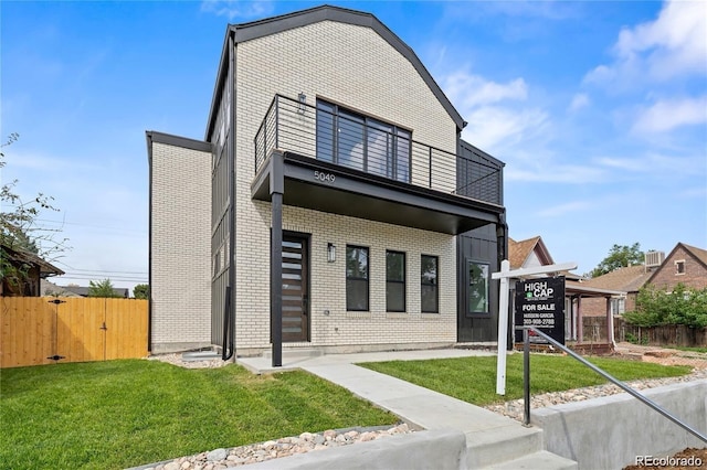 view of front of house featuring a balcony and a front lawn