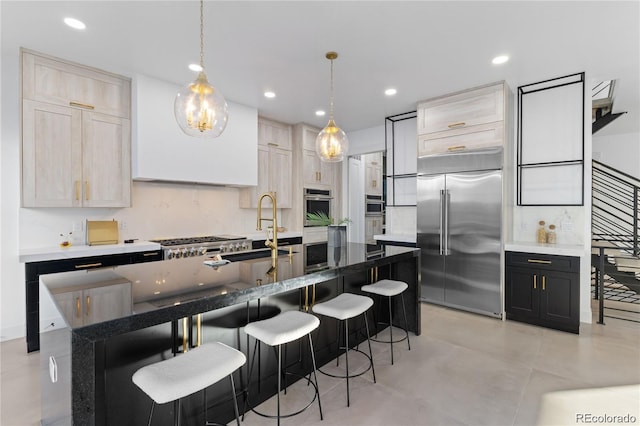 kitchen featuring pendant lighting, light brown cabinets, sink, a center island with sink, and appliances with stainless steel finishes