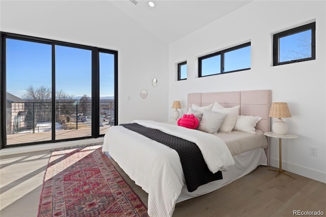 bedroom with lofted ceiling, multiple windows, and hardwood / wood-style flooring