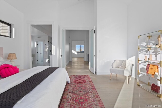 bedroom with light wood-type flooring and a high ceiling