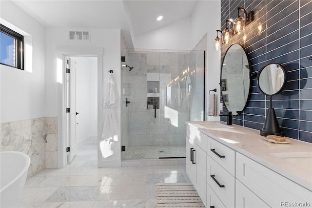 bathroom featuring vanity, separate shower and tub, tile walls, and lofted ceiling