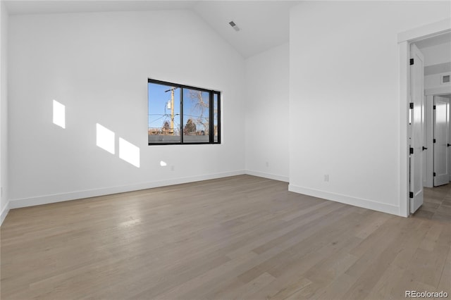 spare room featuring light wood-type flooring and high vaulted ceiling