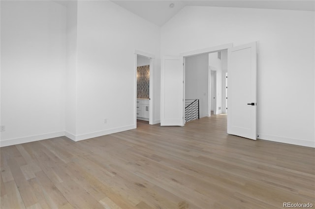 unfurnished room with light wood-type flooring and high vaulted ceiling