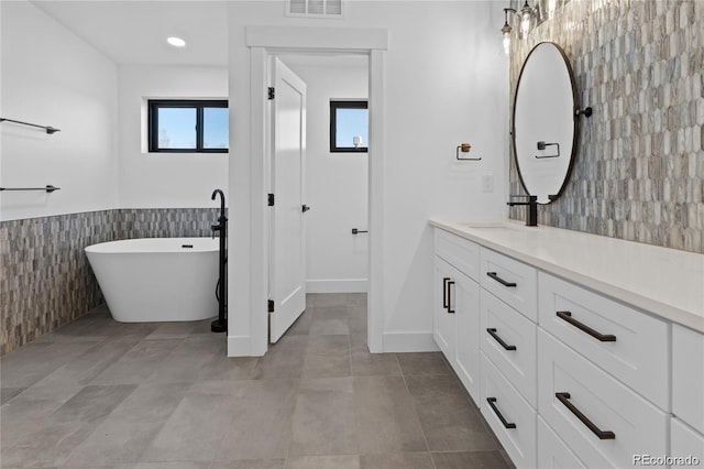 bathroom with a bath, tile walls, tile patterned flooring, and vanity