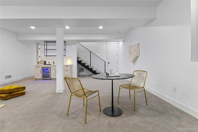 interior space with beverage cooler, light colored carpet, and bar area