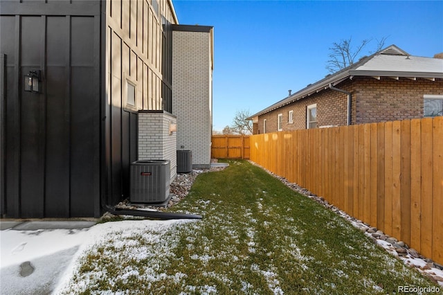 view of snow covered exterior with a yard and central AC unit