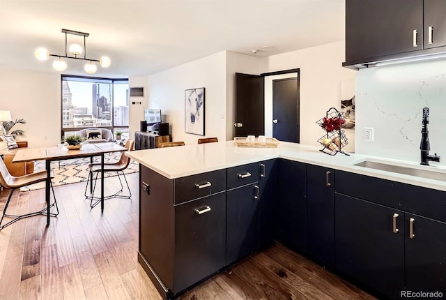 kitchen with sink, hanging light fixtures, kitchen peninsula, and hardwood / wood-style floors