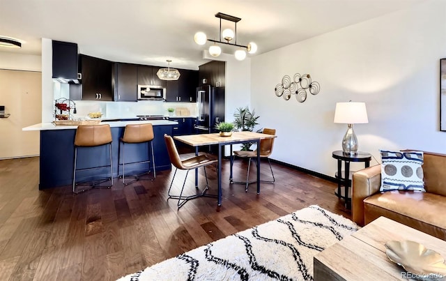 kitchen featuring high end black refrigerator, hanging light fixtures, kitchen peninsula, a breakfast bar area, and dark hardwood / wood-style floors