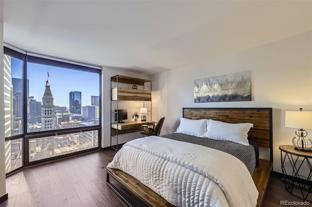 bedroom featuring a wall of windows, built in desk, and dark hardwood / wood-style flooring