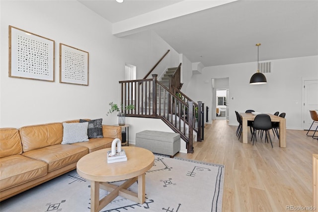 living room featuring beam ceiling and light hardwood / wood-style floors