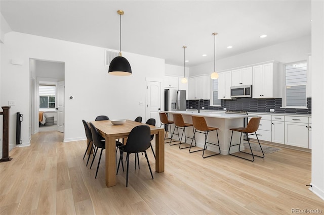 dining area with sink and light wood-type flooring