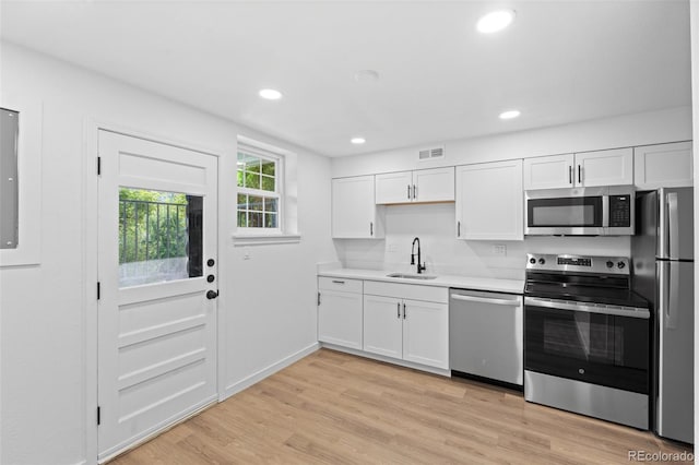 kitchen with sink, light hardwood / wood-style flooring, stainless steel appliances, and white cabinets