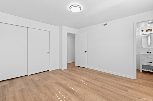 unfurnished bedroom with connected bathroom, light hardwood / wood-style flooring, a closet, and sink