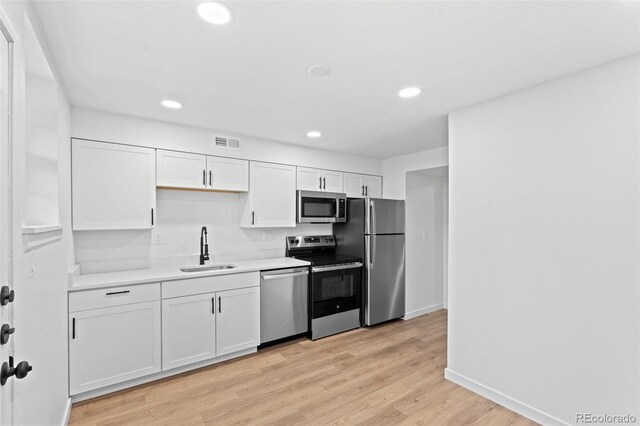 kitchen featuring white cabinetry, stainless steel appliances, light hardwood / wood-style flooring, and sink