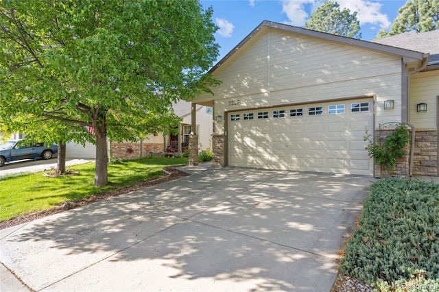 2226 Lily Dr, Loveland, CO 80537 - view of front of house with concrete driveway, stone siding, a garage, and a front lawn