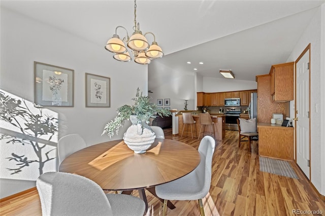 2226 Lily Dr, Loveland, CO 80537 - dining room featuring vaulted ceiling, a chandelier, and light wood-type flooring