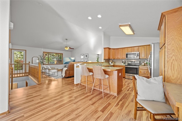 2226 Lily Dr, Loveland, CO 80537 - kitchen featuring stainless steel appliances, open floor plan, a peninsula, a breakfast bar, and light countertops