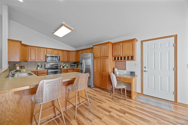 2226 Lily Dr, Loveland, CO 80537 - kitchen with stainless steel appliances, lofted ceiling, a sink, light countertops, and a peninsula