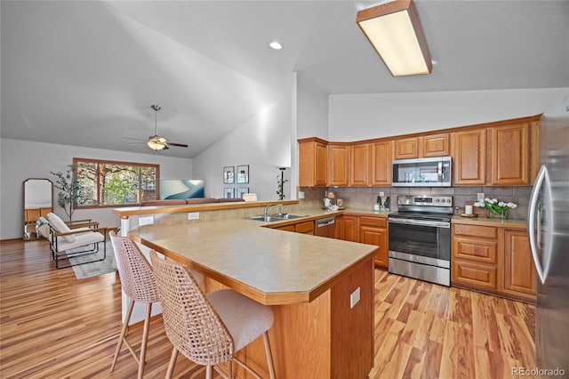 2226 Lily Dr, Loveland, CO 80537 - kitchen featuring appliances with stainless steel finishes, a sink, a peninsula, high vaulted ceiling, and a kitchen bar