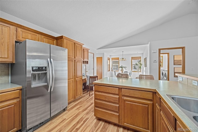 2226 Lily Dr, Loveland, CO 80537 - kitchen featuring stainless steel fridge, vaulted ceiling, a sink, light wood finished floors, and washer and clothes dryer