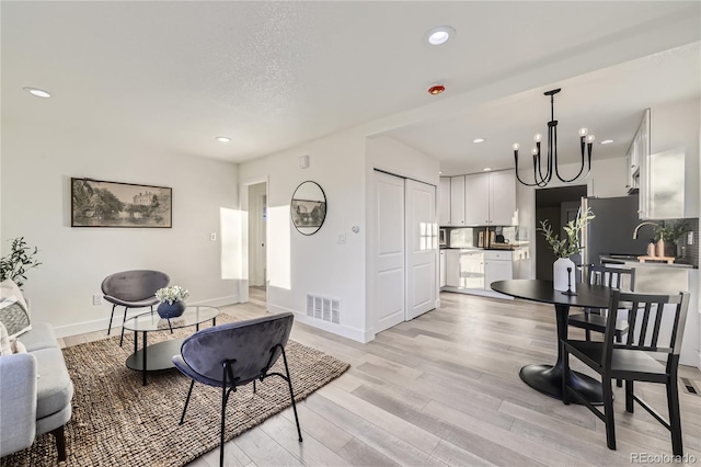 interior space featuring light wood-type flooring, a textured ceiling, and a notable chandelier