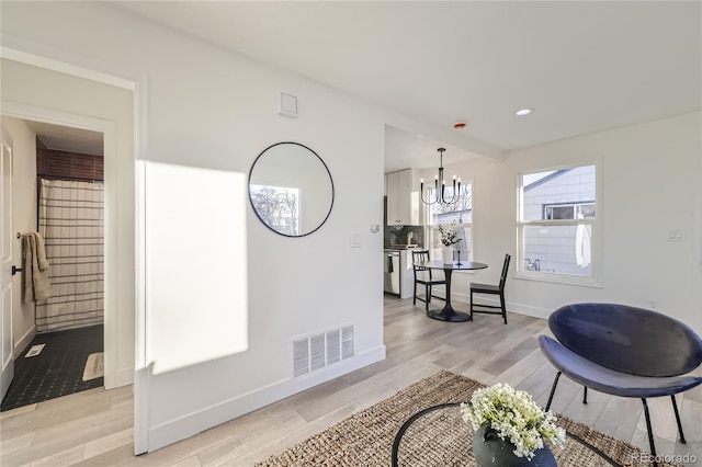 hallway with light hardwood / wood-style floors and a notable chandelier