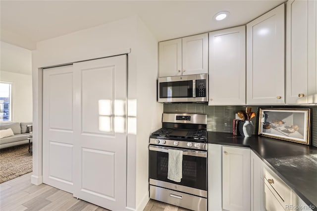 kitchen with stainless steel appliances, light hardwood / wood-style flooring, white cabinetry, and backsplash