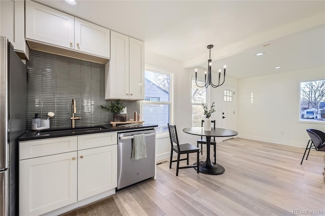 kitchen with decorative backsplash, sink, white cabinetry, hanging light fixtures, and stainless steel appliances