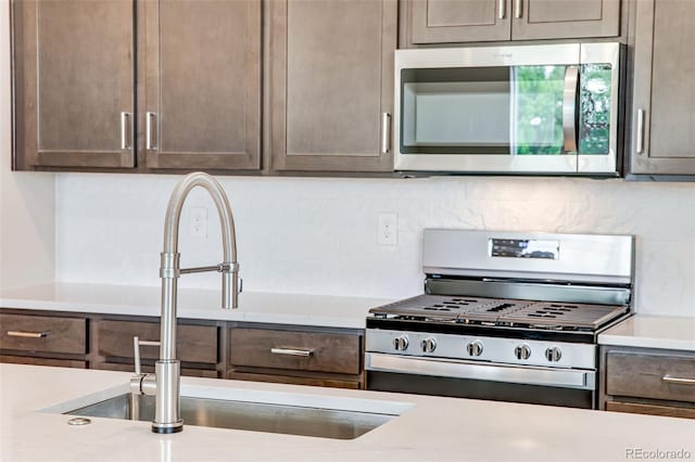 1418 Hudson Pl, Longmont, CO 80501 - kitchen featuring appliances with stainless steel finishes, decorative backsplash, light countertops, and dark brown cabinetry