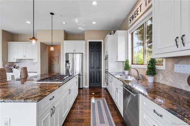 6303 Ellingwood Point Pl, Castle Rock, CO 80108 - kitchen featuring appliances with stainless steel finishes, dark stone counters, white cabinetry, dark wood-type flooring, and tasteful backsplash