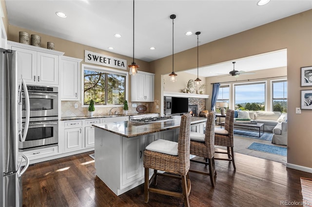6303 Ellingwood Point Pl, Castle Rock, CO 80108 - kitchen featuring stainless steel appliances, open floor plan, healthy amount of natural light, white cabinets, and recessed lighting