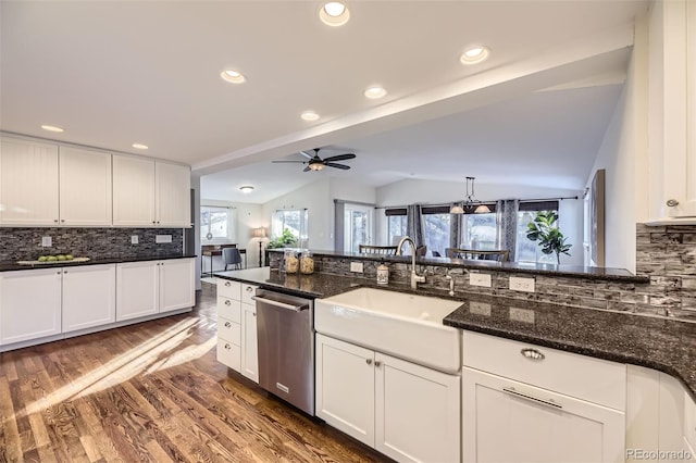 kitchen with sink, vaulted ceiling, dark stone counters, and dishwasher