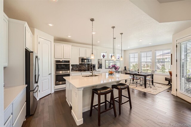 14521 Vancouver Pl, Parker, CO 80134 - kitchen with dark wood-style flooring, recessed lighting, a center island with sink, appliances with stainless steel finishes, and a sink
