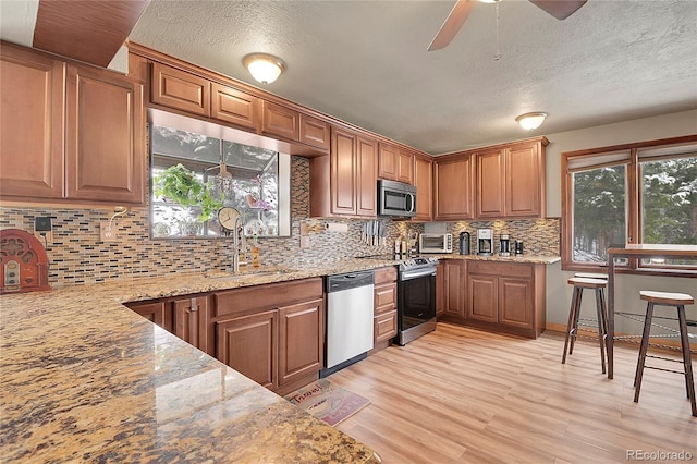 kitchen featuring light hardwood / wood-style floors, appliances with stainless steel finishes, light stone countertops, and sink