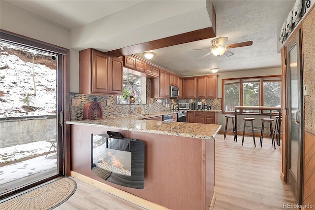 kitchen with light stone countertops, appliances with stainless steel finishes, plenty of natural light, and kitchen peninsula