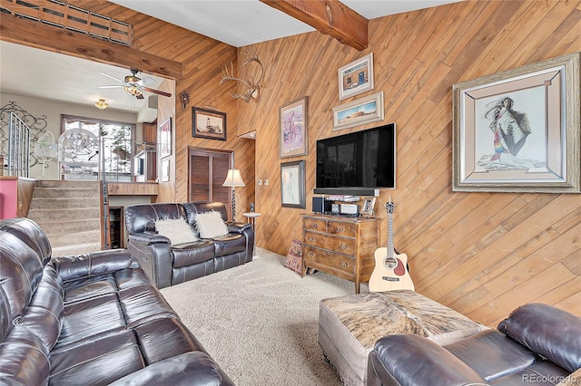 living room with ceiling fan, carpet flooring, beam ceiling, and wood walls