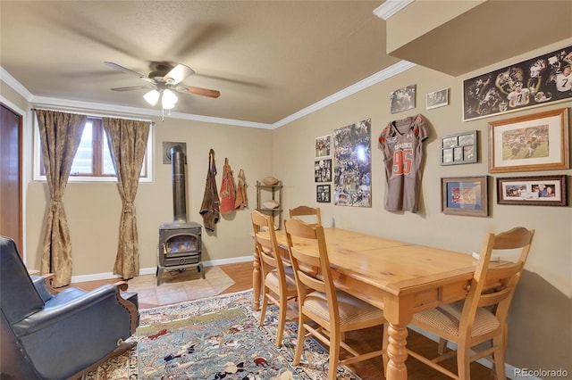 dining room featuring crown molding, ceiling fan, and a wood stove