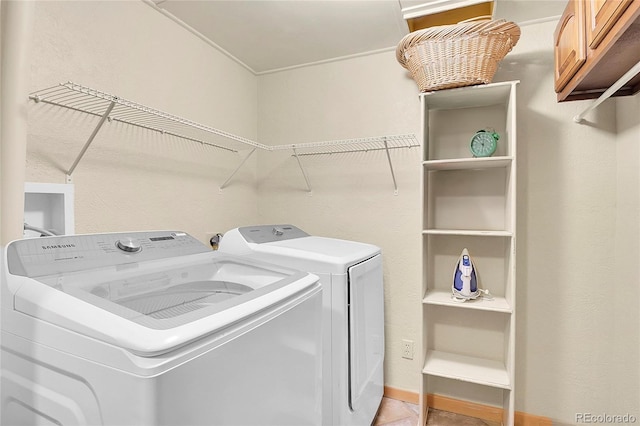 clothes washing area with cabinets and washer and clothes dryer