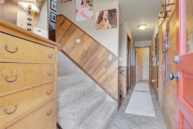 stairs featuring tile patterned floors and wood walls