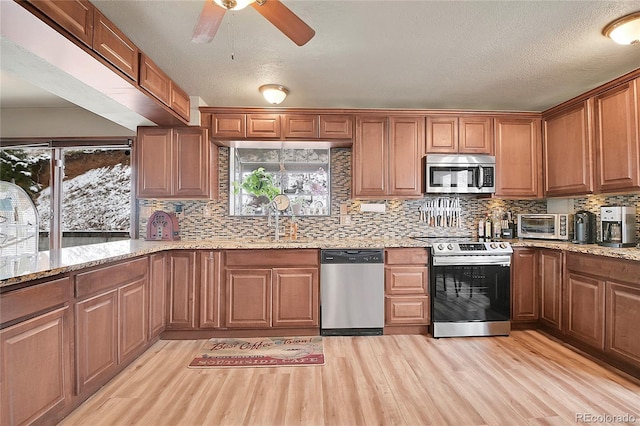 637 Rock Rd, Bailey, CO 80421 - kitchen with stainless steel appliances, light wood-style flooring, tasteful backsplash, ceiling fan, and light stone countertops