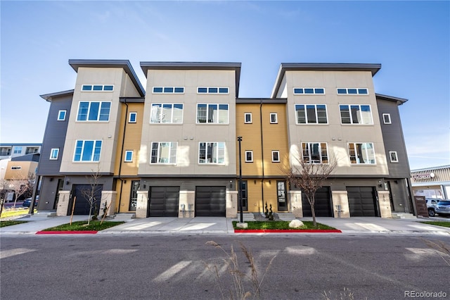 townhome / multi-family property with stucco siding, an attached garage, and driveway