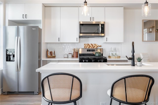 kitchen with a breakfast bar, pendant lighting, stainless steel appliances, and light countertops