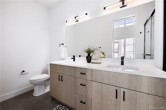 bathroom featuring tile patterned floors, toilet, double vanity, and a sink