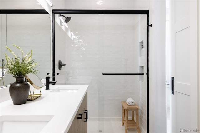 bathroom with double vanity, a shower stall, and a sink