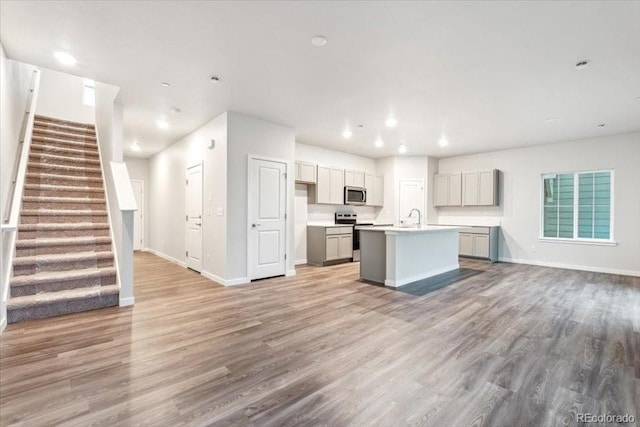 19019 E 94th Pl, Commerce City, CO 80022 - kitchen featuring appliances with stainless steel finishes, a center island with sink, open floor plan, light wood-style flooring, and recessed lighting